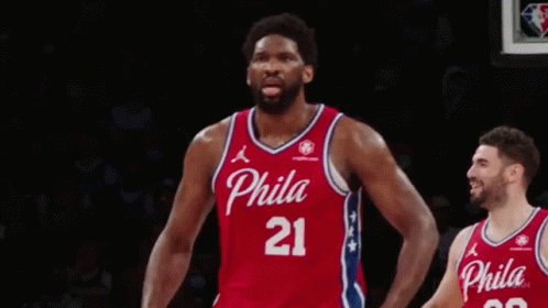 A Philadelphia Basketball Player Is Celebrating A Basket In Front Of A Crowd During A Game . GIF