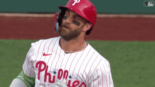 a phillies baseball player wearing a red helmet and a white striped jersey