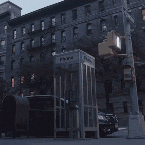 A Phone Booth Sits On The Side Of A Street GIF