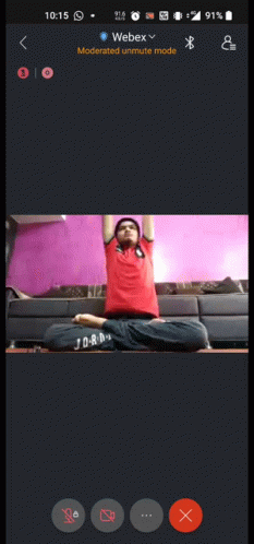 A Phone Screen Shows A Man Sitting In A Lotus Position With His Arms Up GIF
