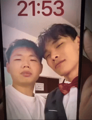 A Phone Screen Shows A Picture Of Two Men And The Time Is 2153 GIF