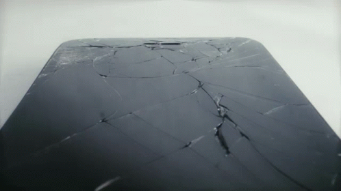 A Phone With A Cracked Screen Is Sitting On A White Surface GIF