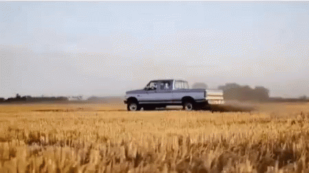 A Pickup Truck Is Driving Through A Wheat Field GIF