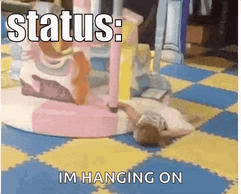 A Picture Of A Baby Laying On The Floor With The Words Status : Im Hanging On GIF