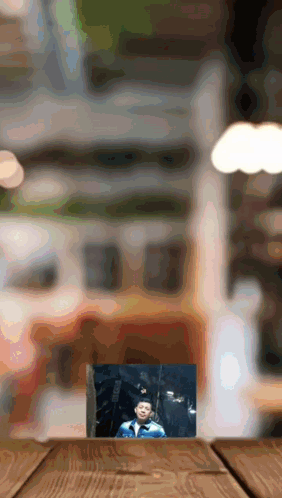 A Picture Of A Boy In A Graduation Cap And Gown On A Wooden Table GIF