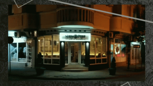 A Picture Of A Building With A Sign That Says Happy Pipe GIF