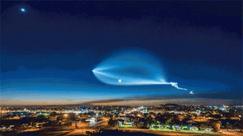 A Picture Of A City At Night With A Blue Sky And A Star In The Background GIF