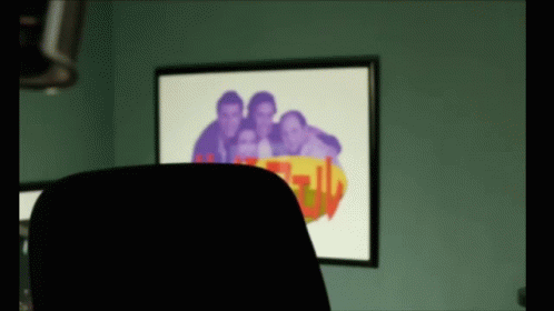 A Picture Of A Group Of People Is Behind A Chair In Front Of A Wall With A Picture On It GIF
