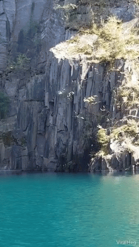 A Picture Of A Lake With A Cliff In The Background And The Words Viralheg GIF