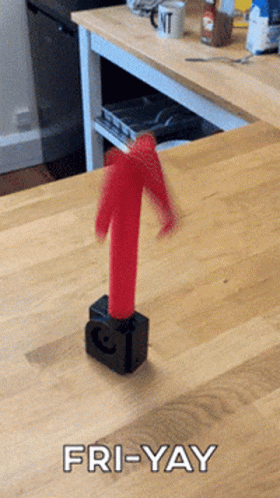 A Picture Of A Red Arrow On A Wooden Table With The Caption Fri-Yay GIF
