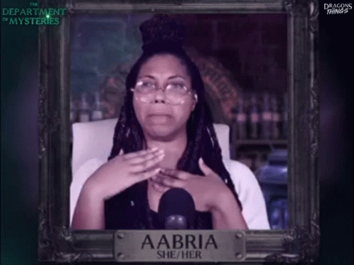 A Picture Of A Woman With Glasses And A Sign That Says Aabri She / Her GIF