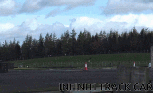 A Picture Of An Infiniti Track Car With A Forest In The Background GIF