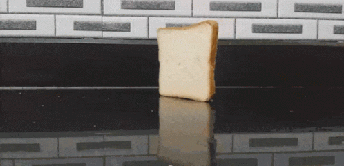 A Piece Of Bread Is Sitting On A Black Counter Top GIF