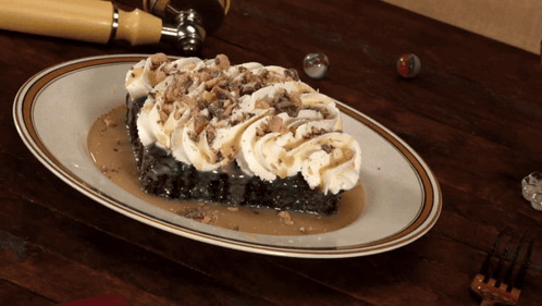 A Piece Of Cake With Whipped Cream And Caramel Sauce On A White Plate GIF
