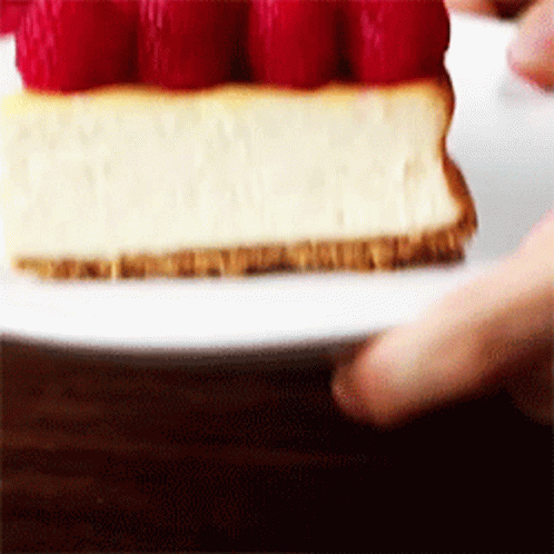 A Piece Of Cheesecake With Raspberries On Top On A White Plate . GIF