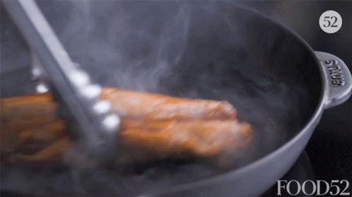 A Piece Of Meat Is Being Cooked In A Pan With The Number 52 On It GIF