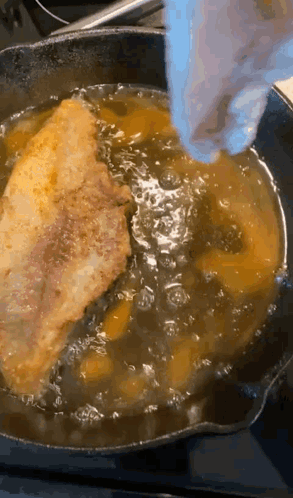 A Piece Of Meat Is Being Cooked In A Skillet With Oil GIF