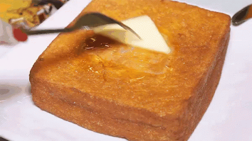 A Piece Of Toast Is Being Buttered With A Fork . GIF