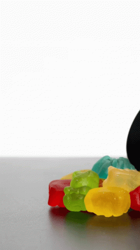 A Pile Of Colorful Gummy Bears On A Table With A White Background GIF