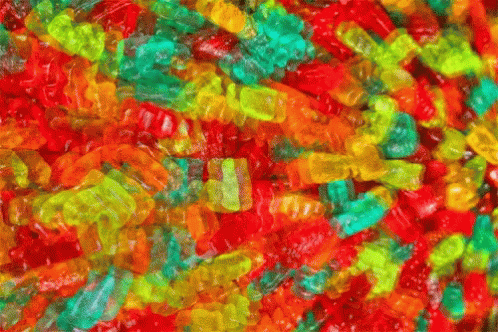 A Pile Of Colorful Gummy Bears With A Green One In The Middle GIF
