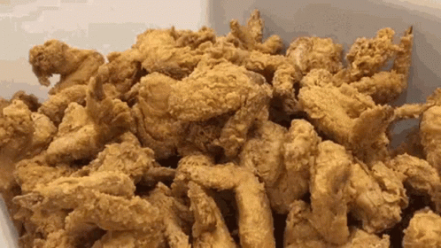 A Pile Of Fried Chicken Is Sitting On A White Surface . GIF