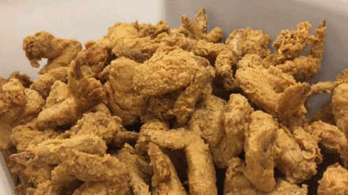 A Pile Of Fried Chicken Pieces In A White Container GIF