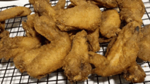 A Pile Of Fried Chicken Wings On A Wire Rack GIF