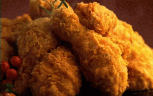 A Pile Of Fried Chicken With Tomatoes And Rosemary On A Table GIF