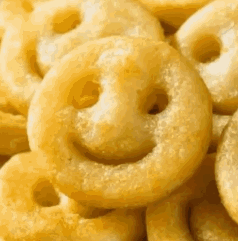 A Pile Of Fried Potatoes With Smiley Faces On Them GIF