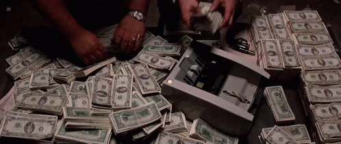 A Pile Of Money Is Sitting On A Table Next To A Stack Of 20 Dollar Bills . GIF