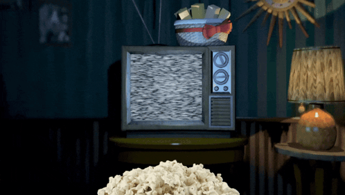 A Pile Of Popcorn Sits On A Table In Front Of An Old Fashioned Television GIF