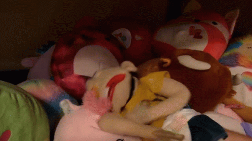 A Pile Of Stuffed Animals Including A Stuffed Animal With A Heart On Its Face GIF