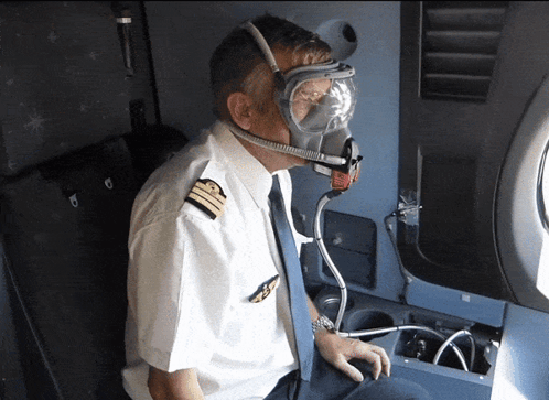 A Pilot Is Wearing A Gas Mask And Goggles While Sitting On An Airplane GIF