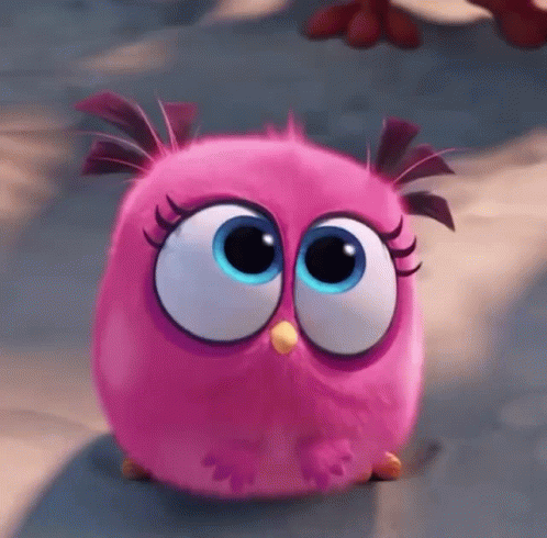 A Pink Angry Bird With Big Blue Eyes Is Sitting On The Ground GIF