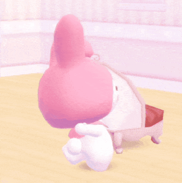 A Pink Bunny With A White Bow On Its Head Is Laying On A Table GIF