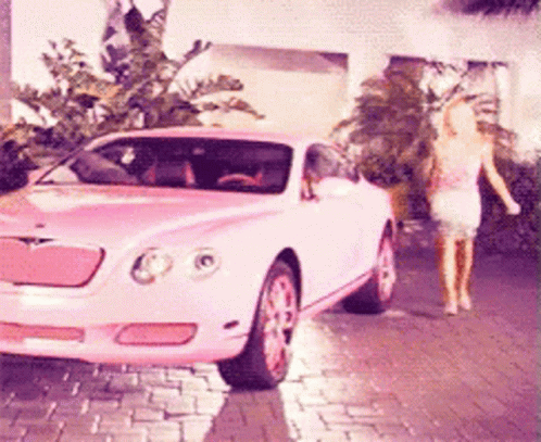 A Pink Car Is Parked On A Brick Driveway GIF