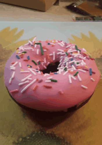 A Pink Donut With Sprinkles And A Hole In It GIF