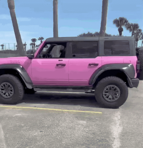A Pink Jeep With Black Trim Is Parked In A Parking Lot GIF