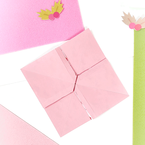 A Pink Origami Bird With Leaves On It Is Sitting On A Table GIF