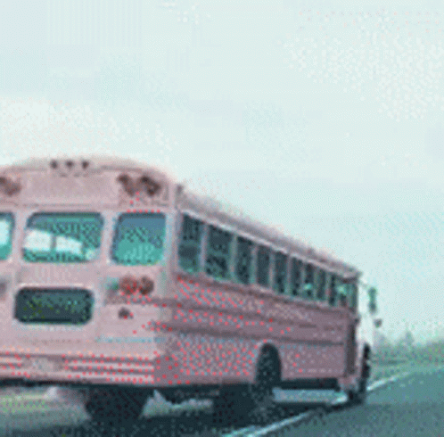 A Pink School Bus Drives Down A Highway GIF