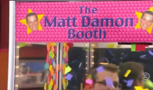 A Pink Sign That Says The Matt Damon Booth Is Above A Man GIF
