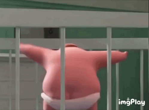 A Pink Stuffed Animal Is Standing In A Cage Behind Bars . GIF