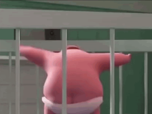 A Pink Stuffed Animal Is Standing In A White Cage Behind Bars . GIF