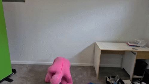 a pink stuffed animal sits in front of a desk in an empty room