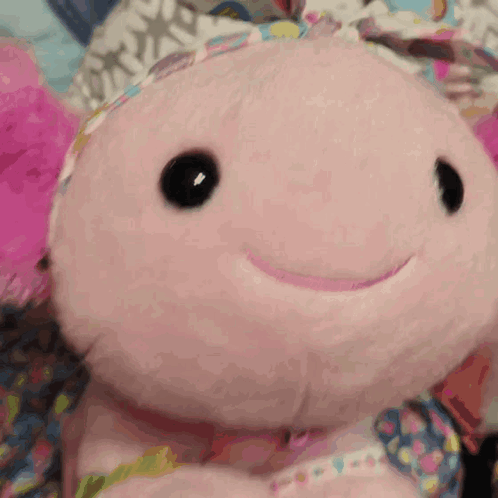 a pink stuffed animal with black eyes and a smile on its face