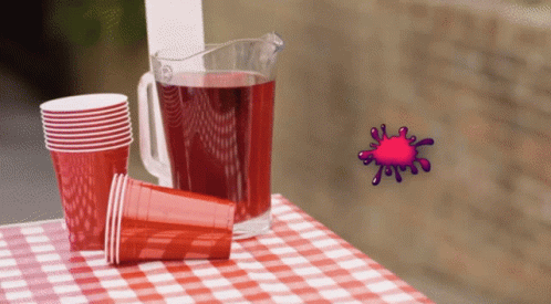 A Pitcher Of Red Liquid Sits On A Checkered Table Cloth GIF