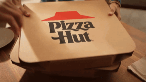 A Pizza Hut Box Sitting On A Wooden Table GIF