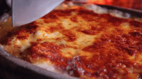 A Pizza With A Lot Of Cheese And Sauce Is Being Scooped Out Of A Pan With A Spatula . GIF