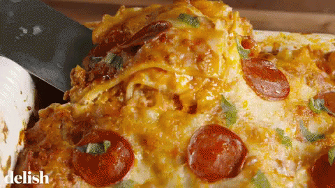 A Pizza With Pepperoni And Cheese Is Being Scooped Out Of A Casserole Dish By A Spatula .. GIF