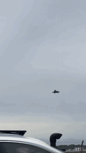 A Plane Is Flying Through A Cloudy Sky . GIF